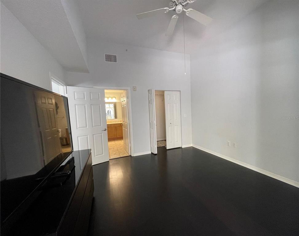A bedroom with dark wood flooring, a ceiling fan, and doors leading to a bathroom and closet — 1064 N TAMIAMI TRAIL UNIT 1122, SARASOTA, FL
