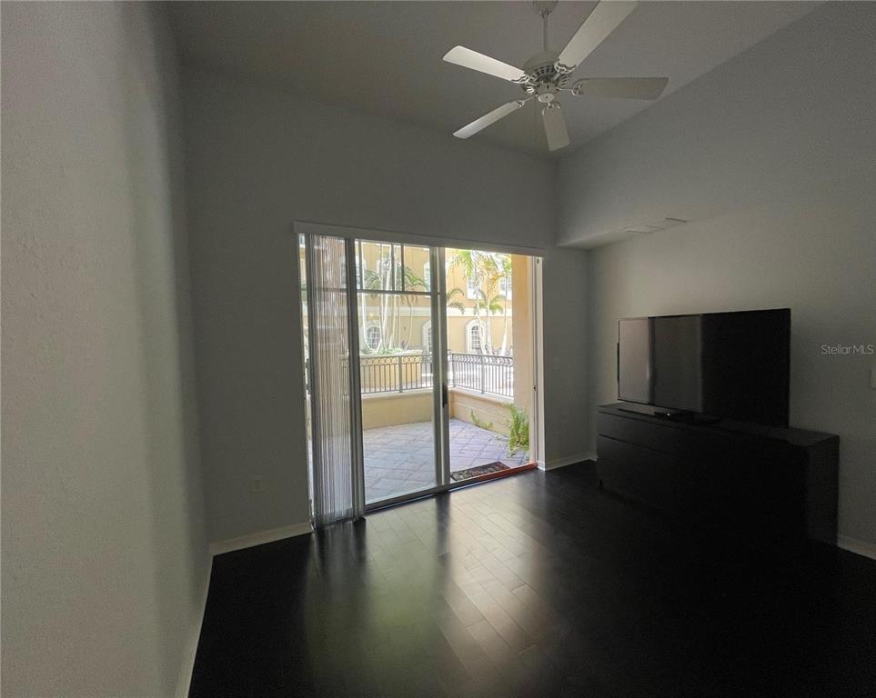 A living room features dark hardwood floors, a ceiling fan, and sliding glass doors to a patio — 1064 N TAMIAMI TRAIL UNIT 1122, SARASOTA, FL
