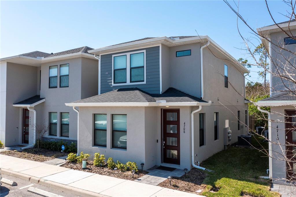 A two-story townhouse with a beige stucco exterior, dark blue siding, and a front entrance — 4708 TERRA ESMERALDA DRIVE, KISSIMMEE, FL
