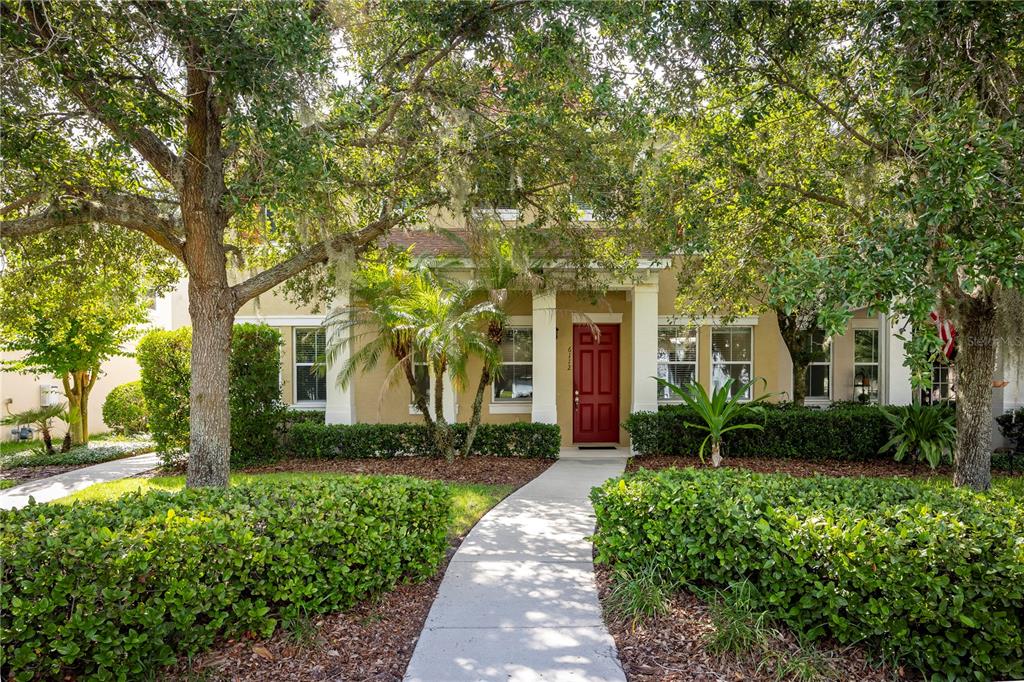 A two-story house with a red front door and a concrete walkway through the yard — 6112 FISHHAWK CROSSING BOULEVARD, LITHIA, FL