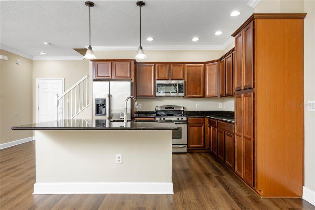A kitchen with wood cabinets, dark countertops, stainless steel appliances, and a central island — 6112 FISHHAWK CROSSING BOULEVARD, LITHIA, FL