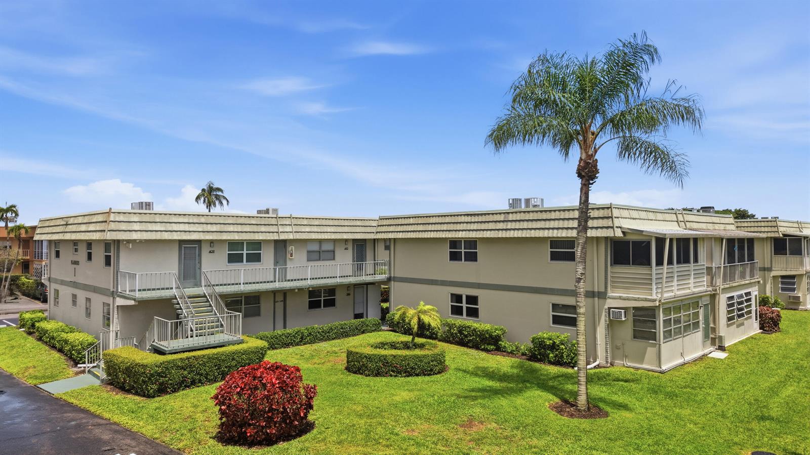 A two-story apartment building with a green lawn, a palm tree, and metal stairs — 387 Flanders I, Delray Beach FL 33484, DELRAY BEACH, FL