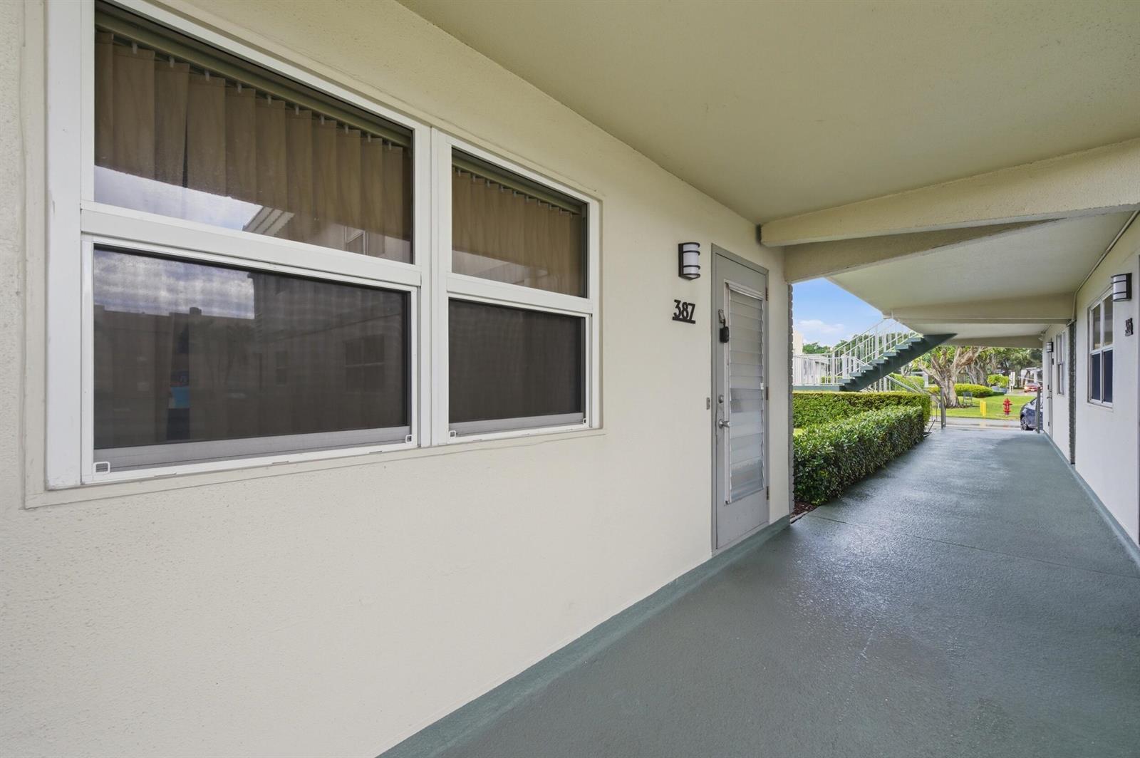 An exterior view of an apartment building walkway with a door numbered 387 — 387 Flanders I, Delray Beach FL 33484, DELRAY BEACH, FL