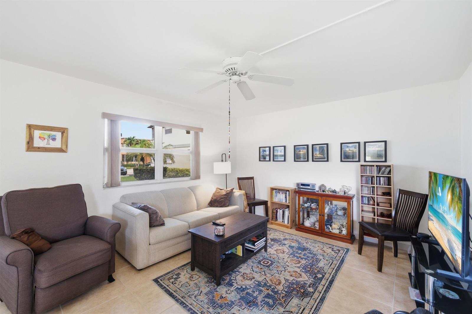 A living room features a beige sofa, brown armchair, area rug, and a television — 387 Flanders I, Delray Beach FL 33484, DELRAY BEACH, FL