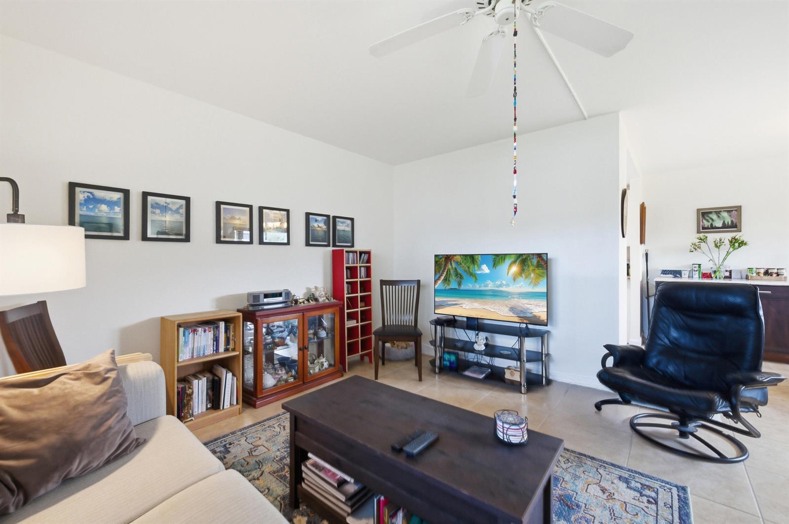 A living room features a sofa, coffee table, television, and a black leather recliner — 387 Flanders I, Delray Beach FL 33484, DELRAY BEACH, FL
