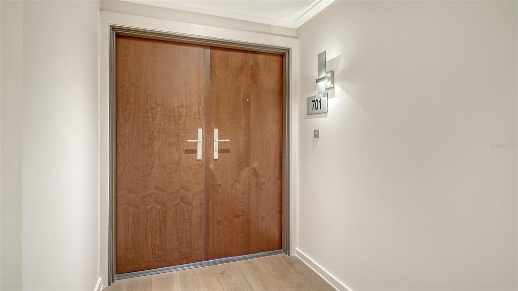 A set of double wood doors with modern handles is located in a hallway — 1211 GULF OF MEXICO DRIVE UNIT 701, LONGBOAT KEY, FL