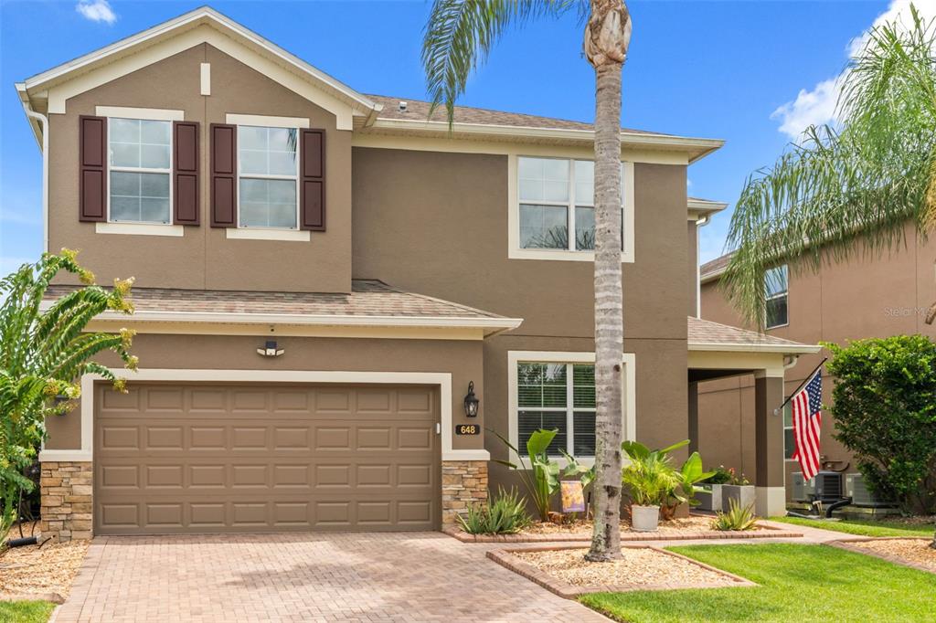 A two-story house with a brown stucco exterior, a two-car garage, and a paved driveway — 648 CORTONA DRIVE, ORLANDO, FL