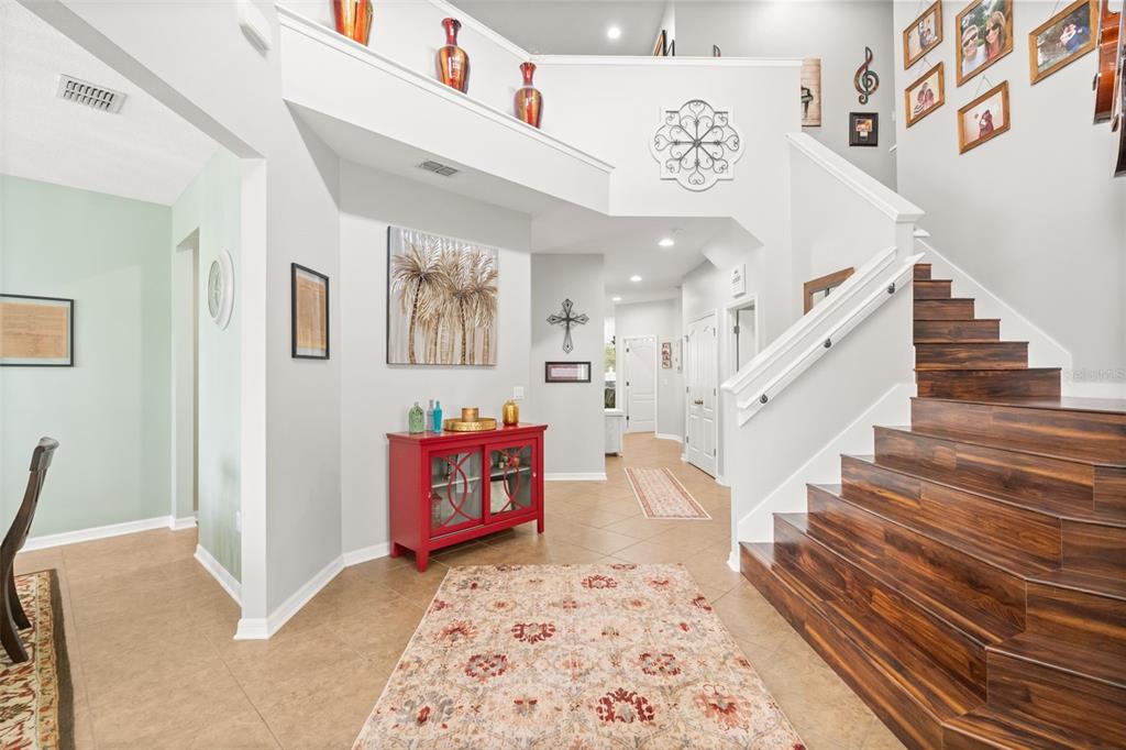 An entryway features a wooden staircase, a red cabinet, and a patterned area rug — 648 CORTONA DRIVE, ORLANDO, FL