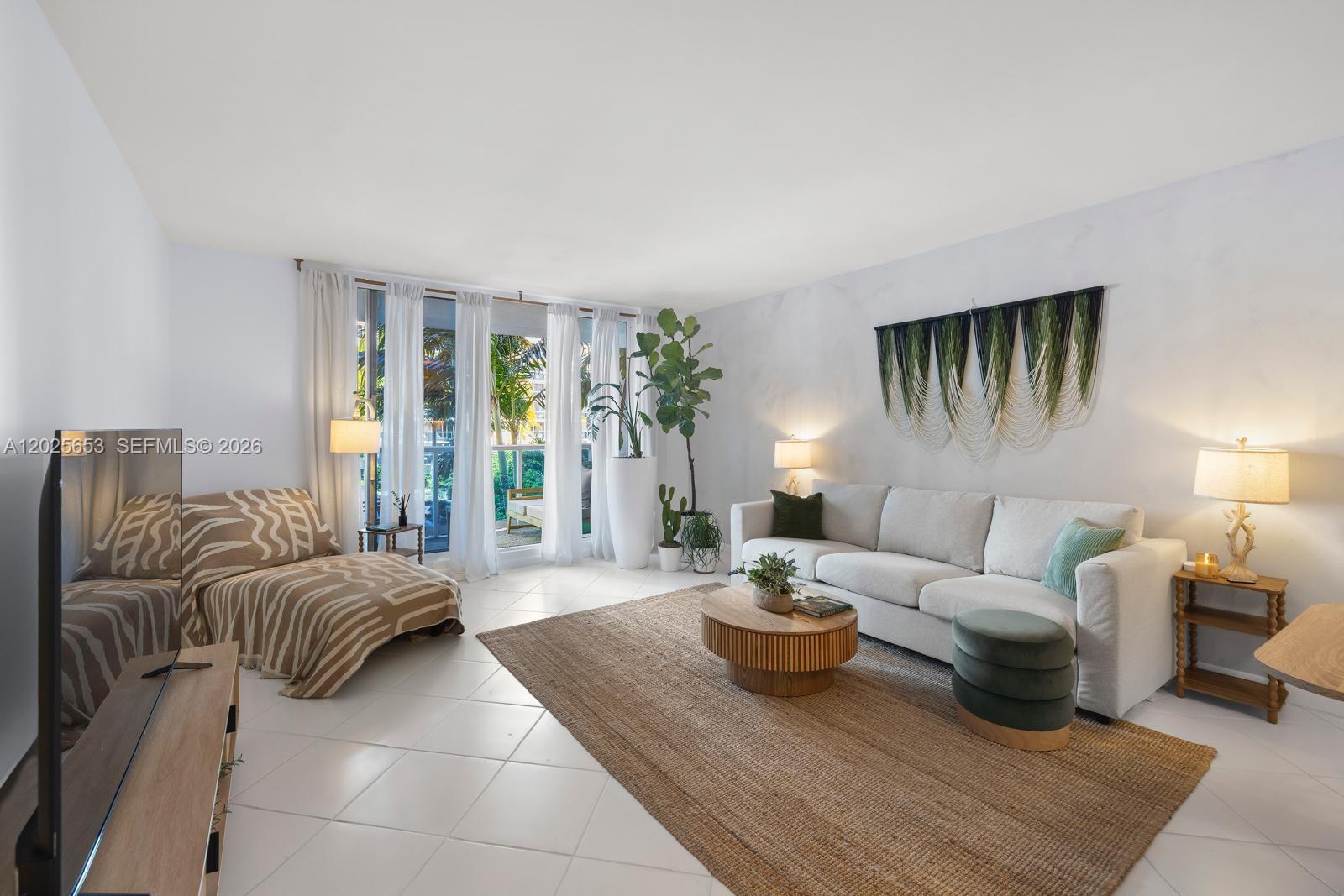 A living room features a beige sofa, a round wooden coffee table, and a large rug — 2301 Collins Ave # 519, Miami Beach FL 33139, MIAMI BEACH, FL