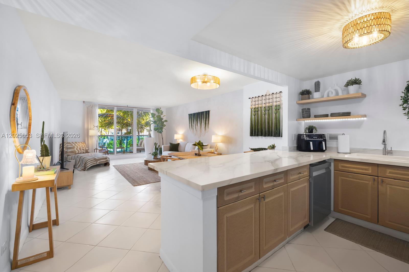 An open-concept living area features a kitchen with wood cabinets and a marble-topped island — 2301 Collins Ave # 519, Miami Beach FL 33139, MIAMI BEACH, FL