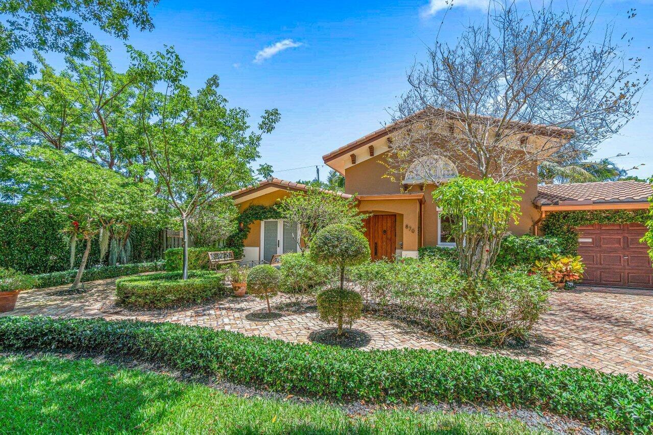 A tan house with a tiled roof and a brick driveway surrounded by landscaped gardens — 870 NW 7th Street, Boca Raton FL 33486, BOCA RATON, FL