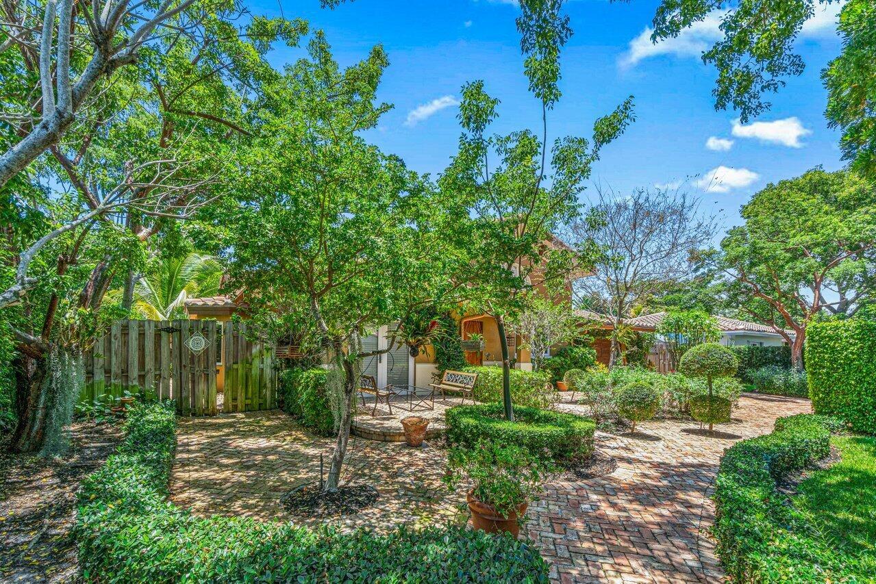 A brick patio with a wooden gate and lush landscaping leads to a residential home — 870 NW 7th Street, Boca Raton FL 33486, BOCA RATON, FL