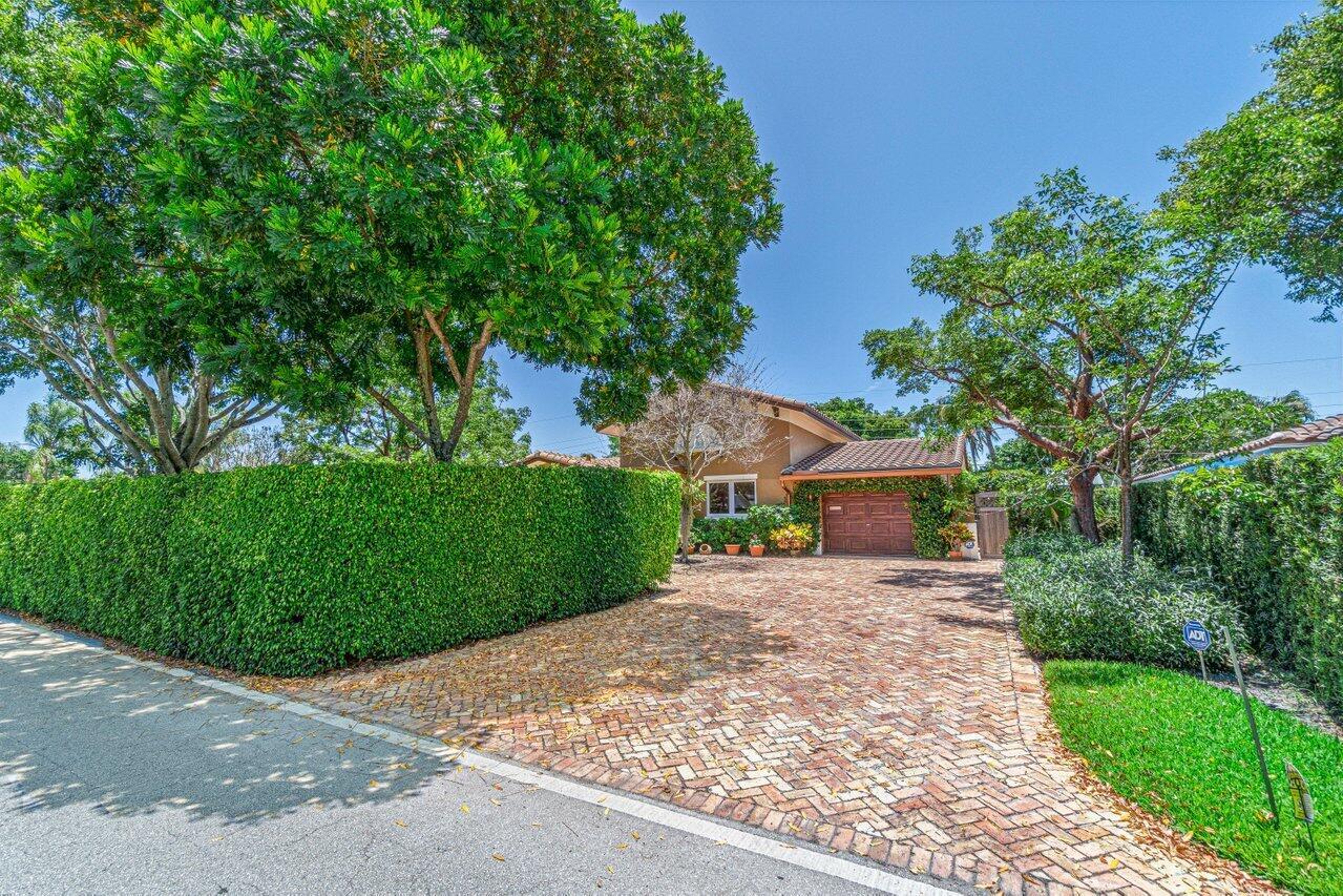 A house with a brick driveway and a large hedge sits behind a street — 870 NW 7th Street, Boca Raton FL 33486, BOCA RATON, FL