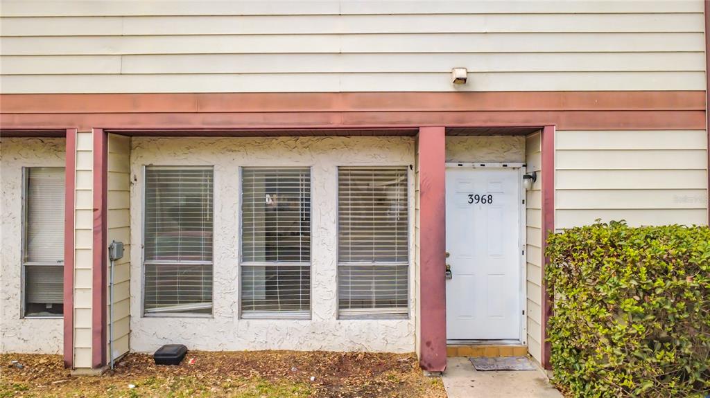 The exterior of a townhouse features beige horizontal siding, three windows with blinds, and a white front door — 3968 CRAYRICH CIRCLE UNIT C3, ORLANDO, FL