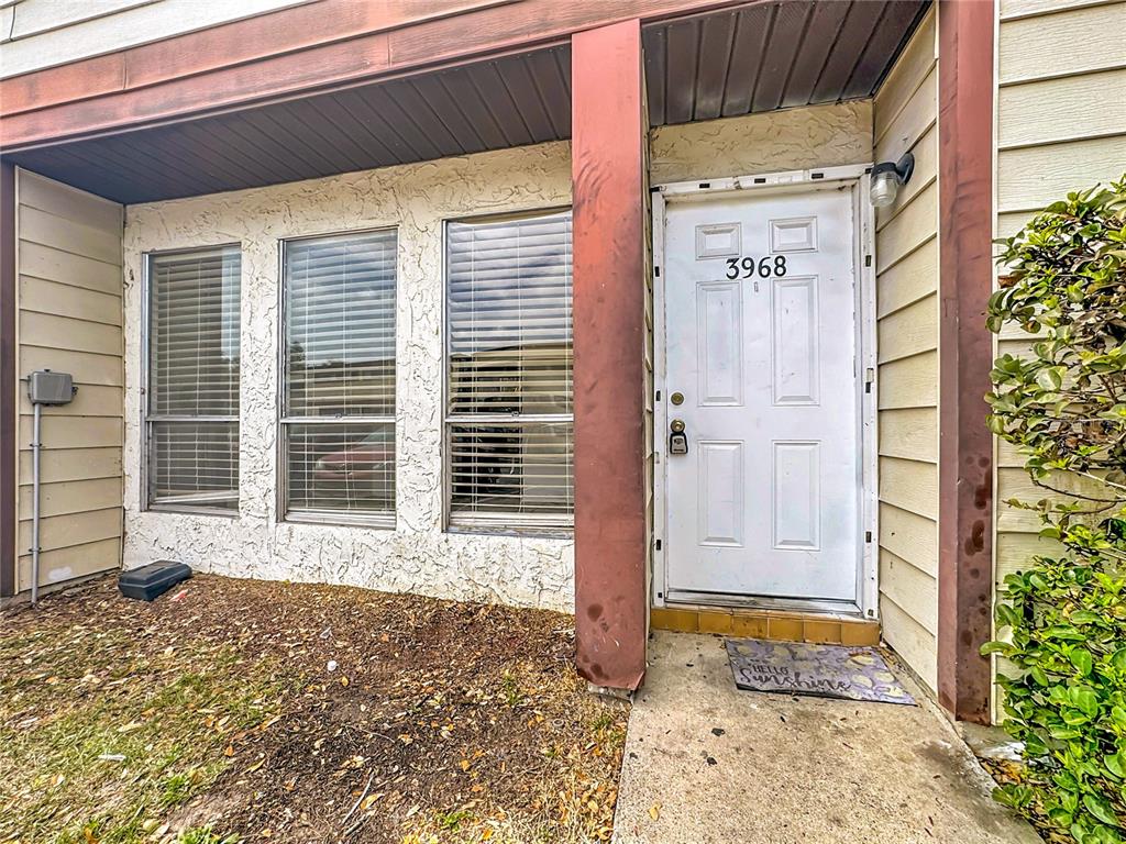 The exterior of a home features a white front door, three windows, and tan siding — 3968 CRAYRICH CIRCLE UNIT C3, ORLANDO, FL