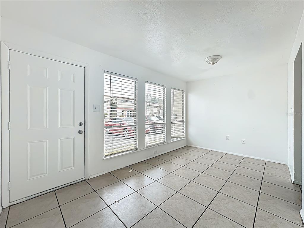 An empty room with white walls, tiled floors, a white door, and three windows — 3968 CRAYRICH CIRCLE UNIT C3, ORLANDO, FL
