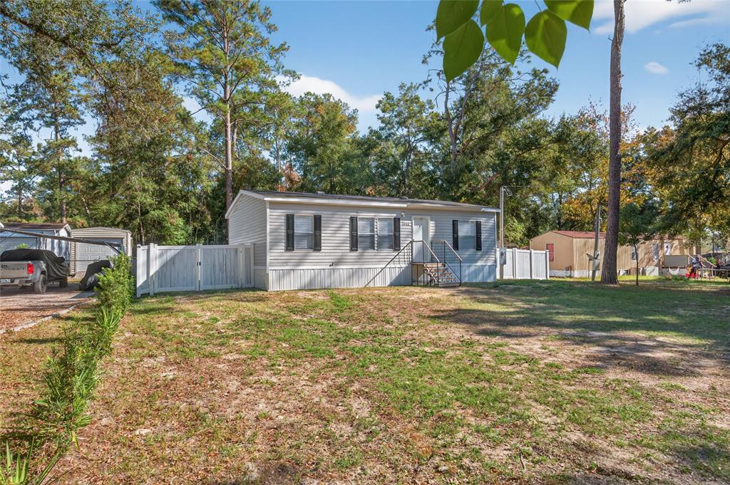 A single-story manufactured home with light siding stands on a grassy lot with trees — 3883 SE 55TH COURT, OCALA, FL