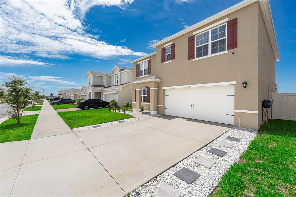 A two-story suburban house with a tan stucco exterior, white garage door, and concrete driveway — 4641 BERNARD BOULEVARD, HAINES CITY, FL