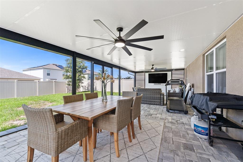 A covered patio features a dining set, outdoor furniture, a television, and a ceiling fan — 4641 BERNARD BOULEVARD, HAINES CITY, FL