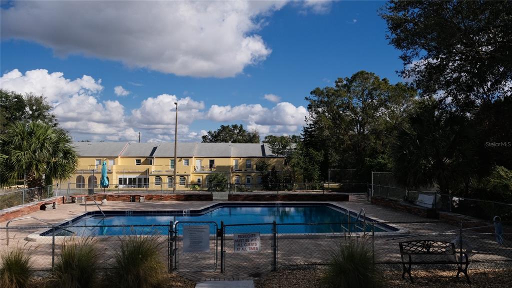 An outdoor swimming pool surrounded by a chain-link fence with a multi-story building behind it — 5850 CYPRESS GARDENS BOULEVARD UNIT 304, WINTER HAVEN, FL