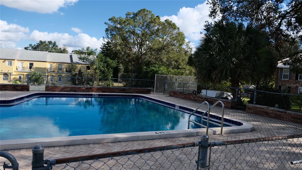 A rectangular swimming pool with a brick deck is enclosed by a chain-link fence — 5850 CYPRESS GARDENS BOULEVARD UNIT 304, WINTER HAVEN, FL
