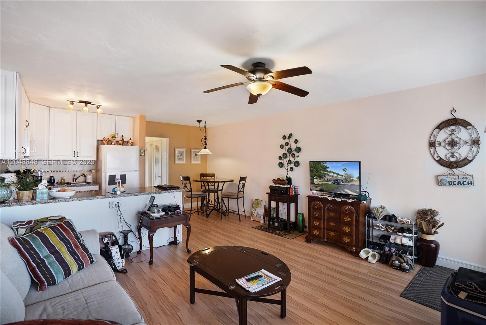 An open-concept living room and kitchen area with light wood flooring and a ceiling fan — 1000 SW 11 AVE # 17E, Hallandale Beach FL 33009, HALLANDALE BEACH, FL