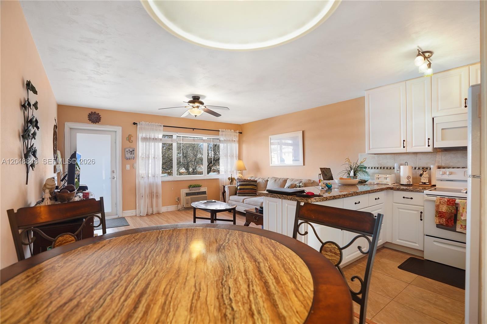 An open-concept living area features a kitchen with white cabinets, a dining table, and seating — 1000 SW 11 AVE # 17E, Hallandale Beach FL 33009, HALLANDALE BEACH, FL