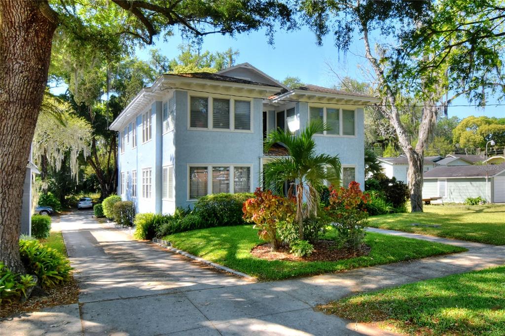 A two-story light blue house with a driveway and landscaping sits under large trees — 211 E PARK STREET, LAKELAND, FL