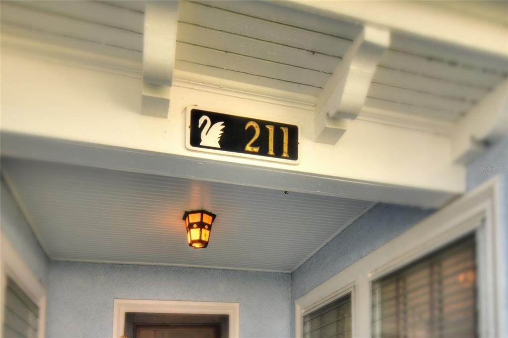 A house number sign with a swan icon hangs above a porch light — 211 E PARK STREET, LAKELAND, FL