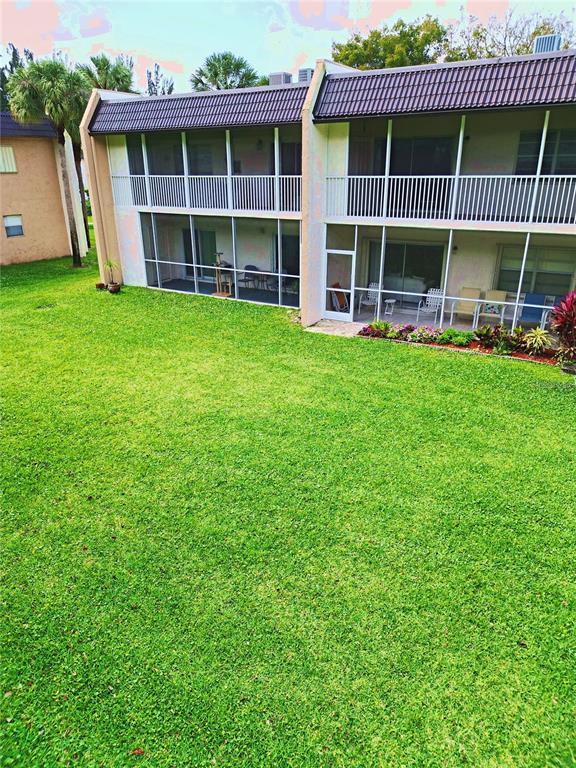 A two-story apartment building features screened-in balconies and patios overlooking a large grassy lawn — 140 LAKE MERYL DRIVE UNIT 233, WEST PALM BEACH, FL