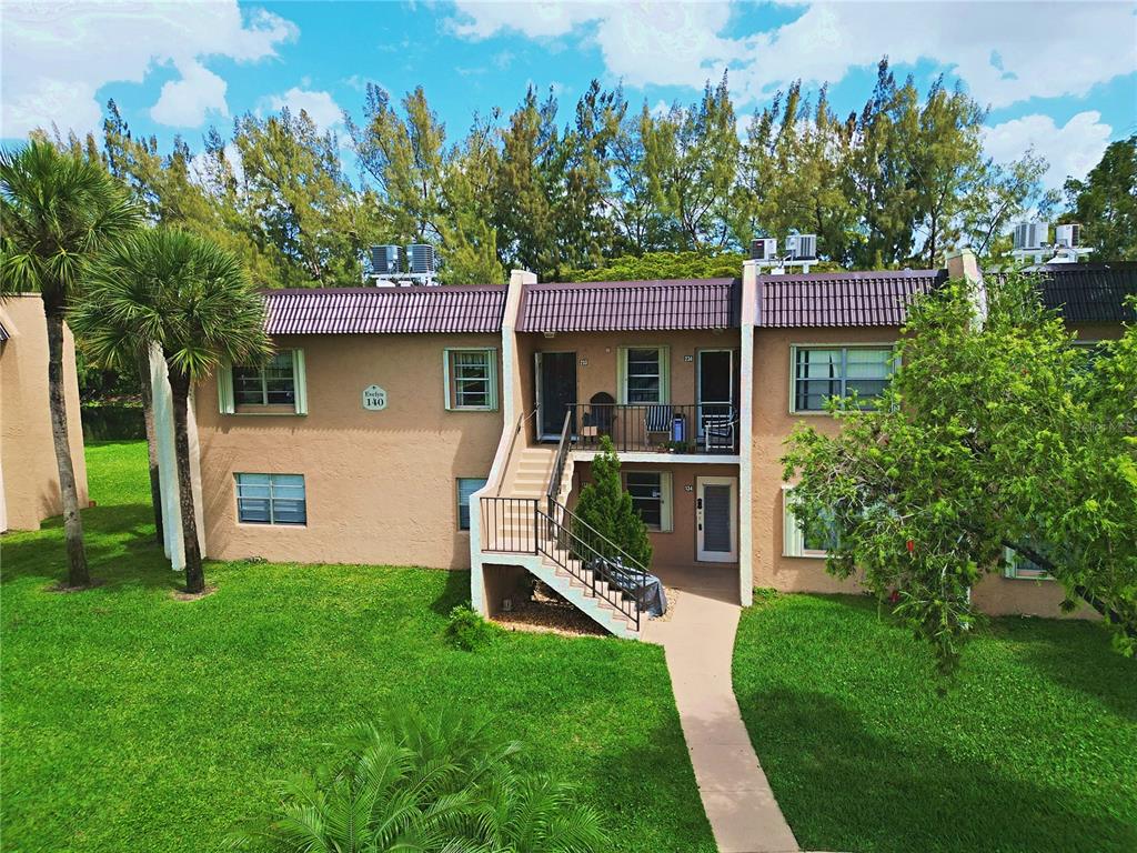 An exterior view of a two-story apartment building with tan stucco walls and stairs — 140 LAKE MERYL DRIVE UNIT 233, WEST PALM BEACH, FL