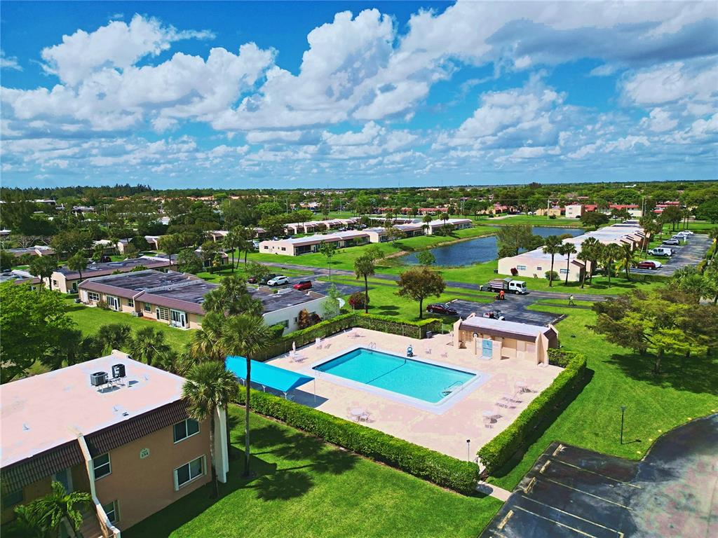 An aerial view of a residential complex featuring a swimming pool, parking lots, and landscaping — 140 LAKE MERYL DRIVE UNIT 233, WEST PALM BEACH, FL