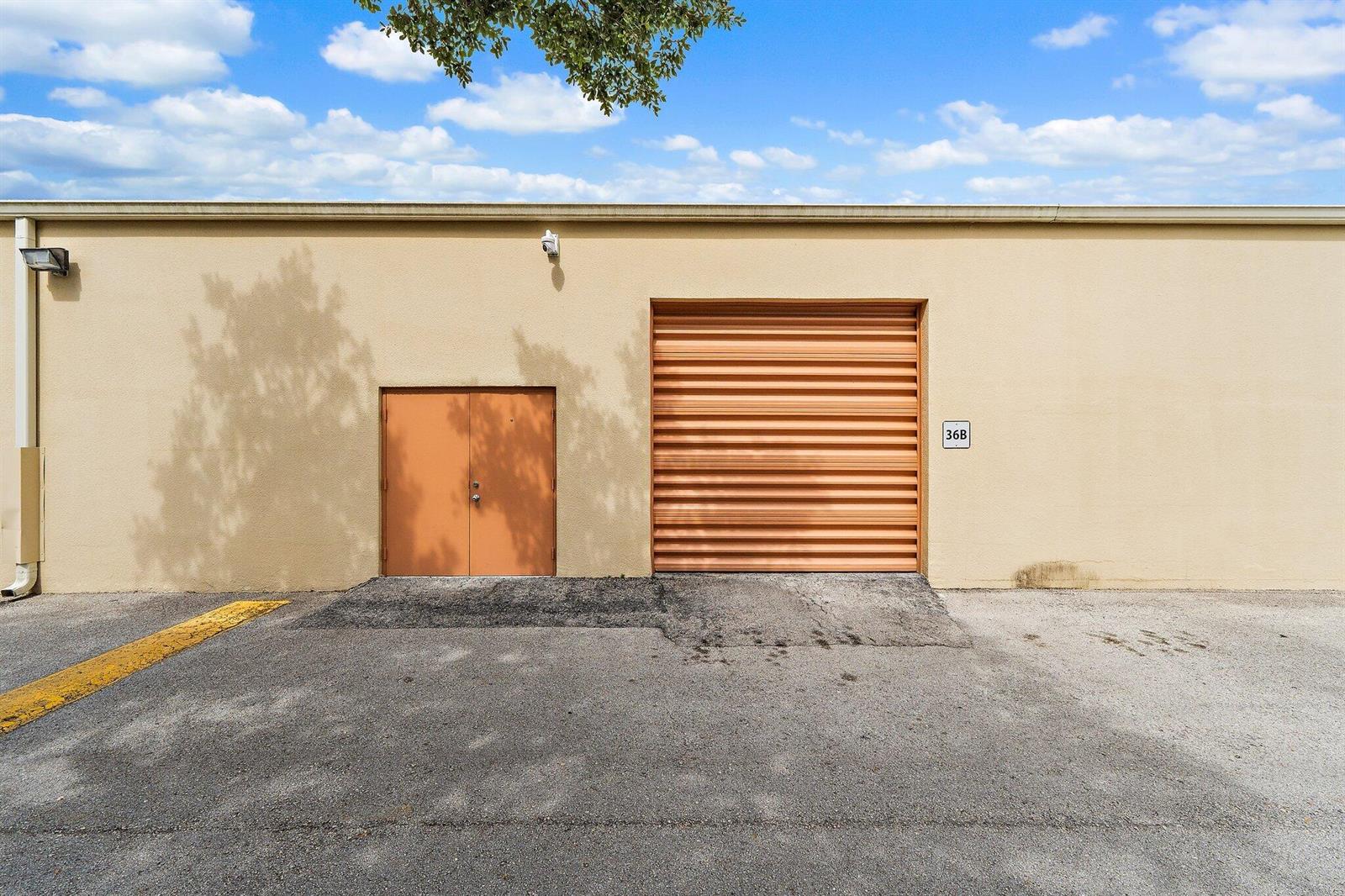 The exterior of a commercial building features a metal roll-up door and double doors — 803 Maplewood Drive # 36b, Jupiter FL 33458, JUPITER, FL