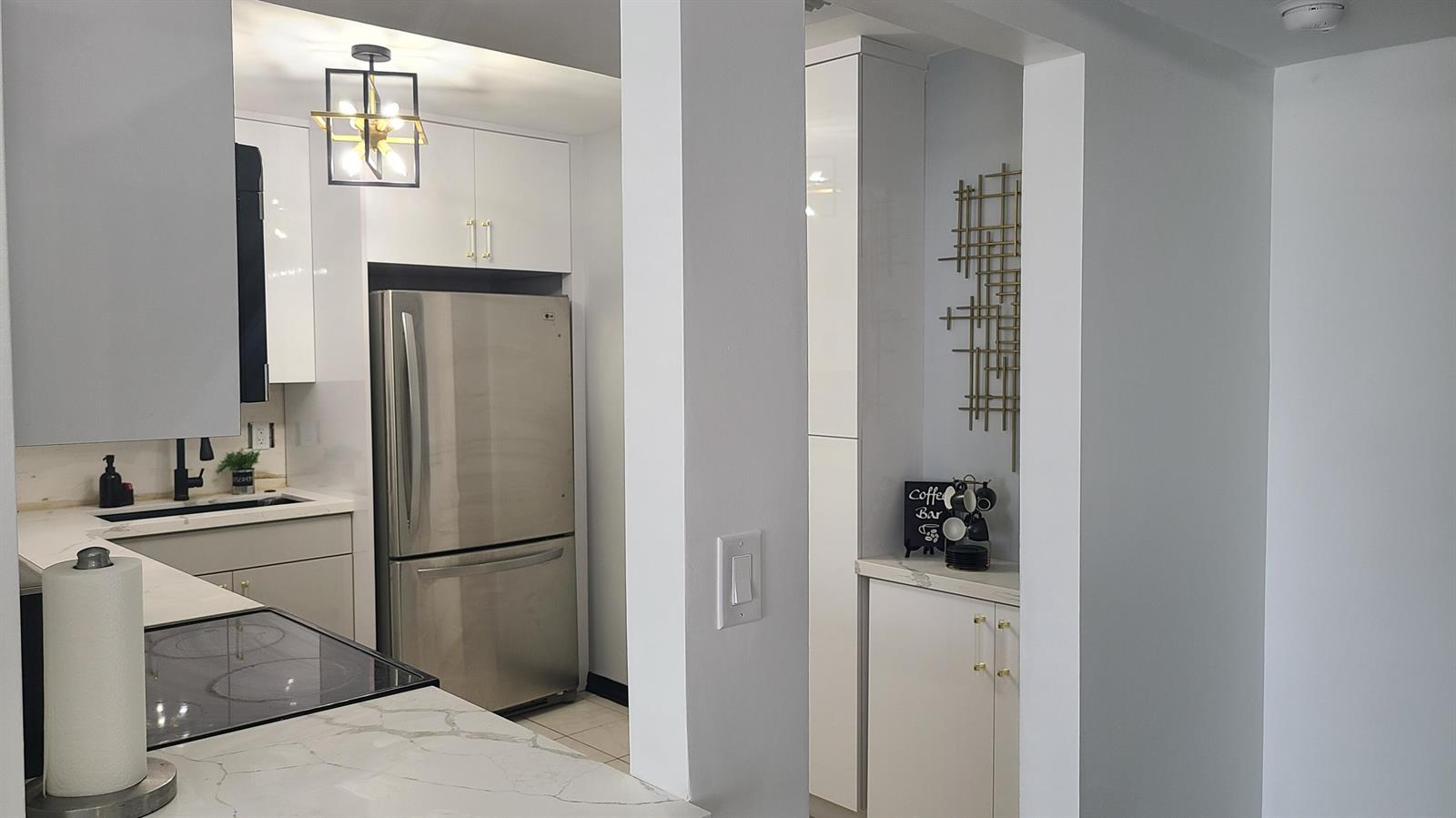 A modern kitchen features white cabinetry, stainless steel appliances, and a marble-patterned countertop — 2500 Parkview Drive # 802, Hallandale Beach FL 33009, HALLANDALE BEACH, FL