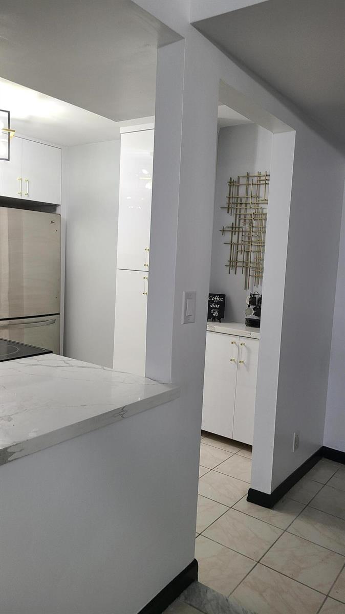 A kitchen features white cabinetry, stainless steel appliances, and a marble-patterned countertop — 2500 Parkview Drive # 802, Hallandale Beach FL 33009, HALLANDALE BEACH, FL