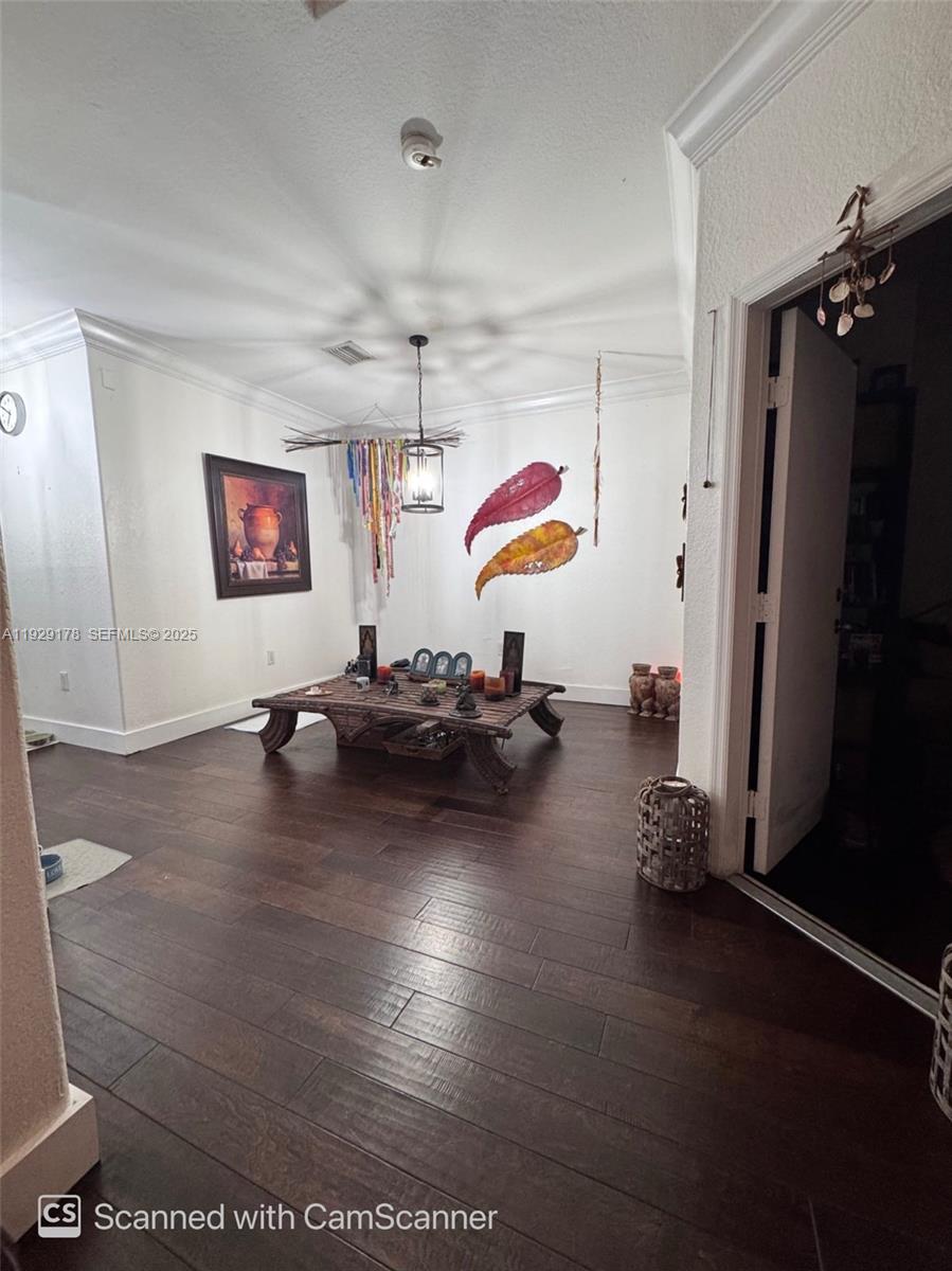 A room with dark wood flooring features a low wooden table and wall-mounted leaf decor — 15064 SW 8th Ln, Miami FL 33194, MIAMI, FL