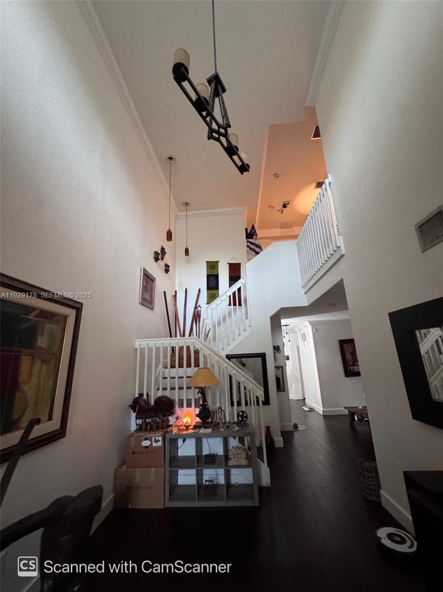 A high-ceilinged foyer features a staircase, dark wood flooring, and a multi-light chandelier — 15064 SW 8th Ln, Miami FL 33194, MIAMI, FL