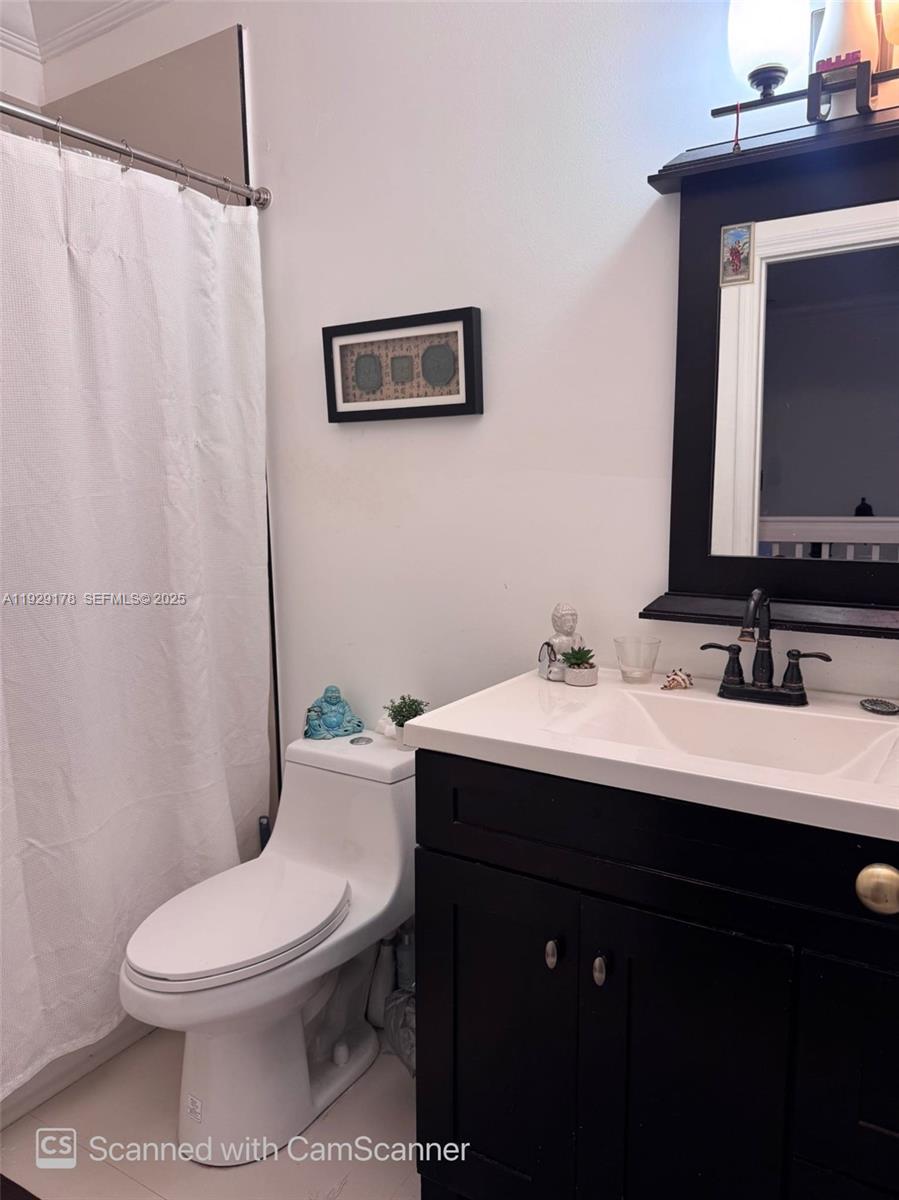 A bathroom features a white toilet, a black vanity with a white sink, and a shower curtain — 15064 SW 8th Ln, Miami FL 33194, MIAMI, FL