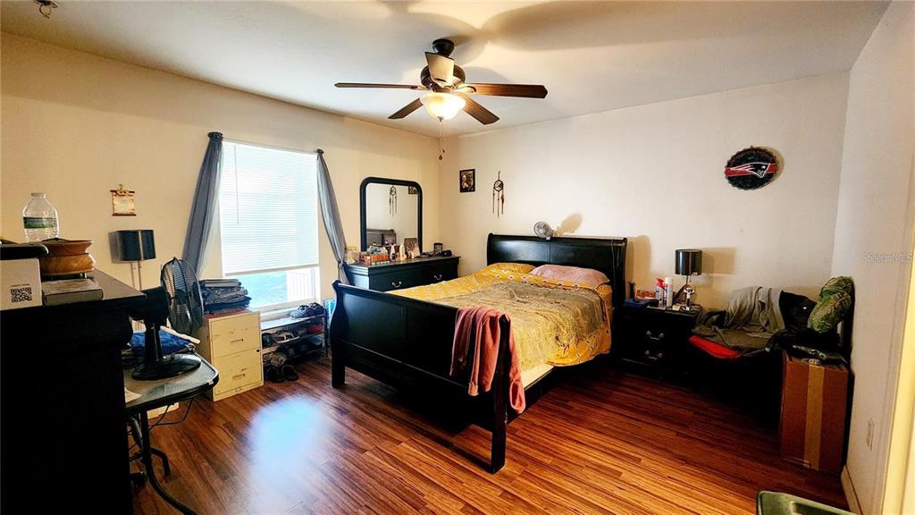 A bedroom features a black bed frame, wood-look flooring, a ceiling fan, and a window — 11216 NW 8TH LANE, OCALA, FL