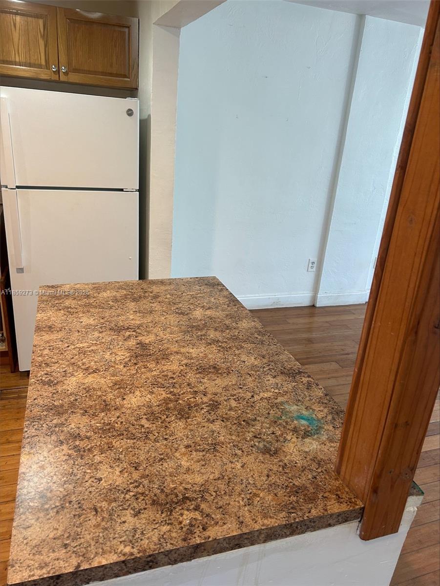 A kitchen counter with a brown speckled laminate top sits next to a white refrigerator — 2175 NE 170th St # 202, North Miami Beach FL 33162, NORTH MIAMI BEACH, FL