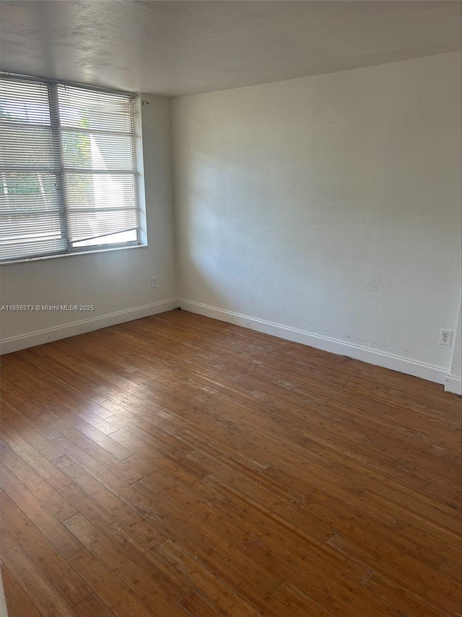 An empty room features light wood flooring, white walls, and a window with blinds — 2175 NE 170th St # 202, North Miami Beach FL 33162, NORTH MIAMI BEACH, FL