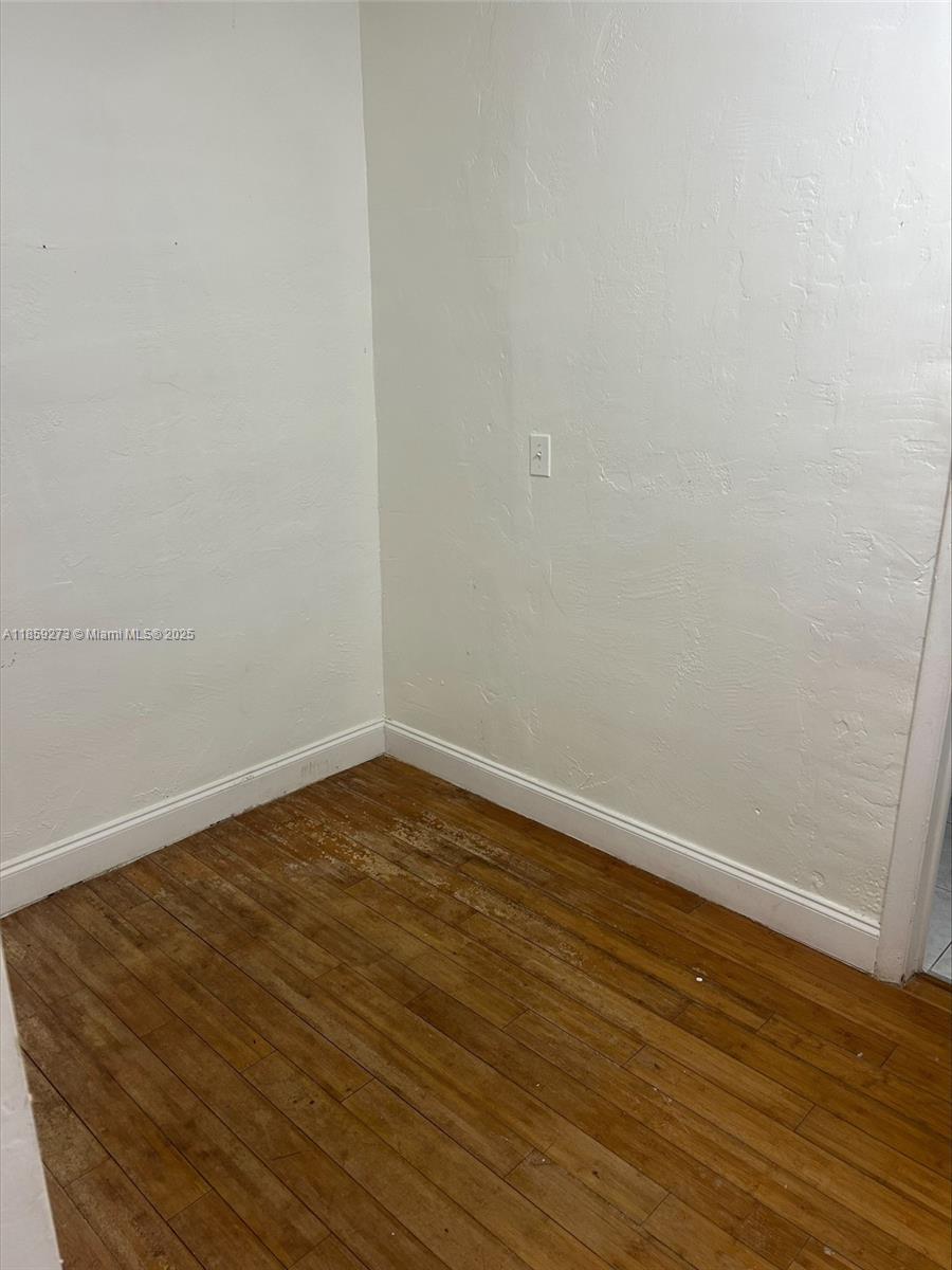 This room features light-colored walls, a single electrical outlet, and worn hardwood flooring — 2175 NE 170th St # 202, North Miami Beach FL 33162, NORTH MIAMI BEACH, FL