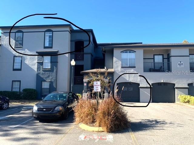 A multi-story apartment building exterior features a dark car parked in front of garages — 8414 LUCUYA WAY UNIT 308, TEMPLE TERRACE, FL