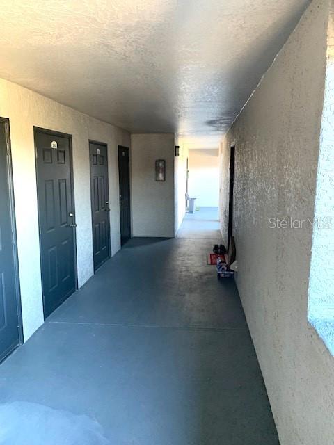 An outdoor apartment corridor features dark doors, light-colored walls, and a gray concrete floor — 8414 LUCUYA WAY UNIT 308, TEMPLE TERRACE, FL