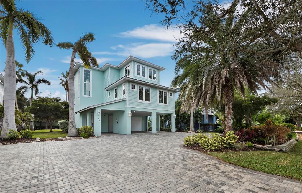 A three-story light blue house with a paved driveway and palm trees in the yard — 333 FIREHOUSE COURT, LONGBOAT KEY, FL