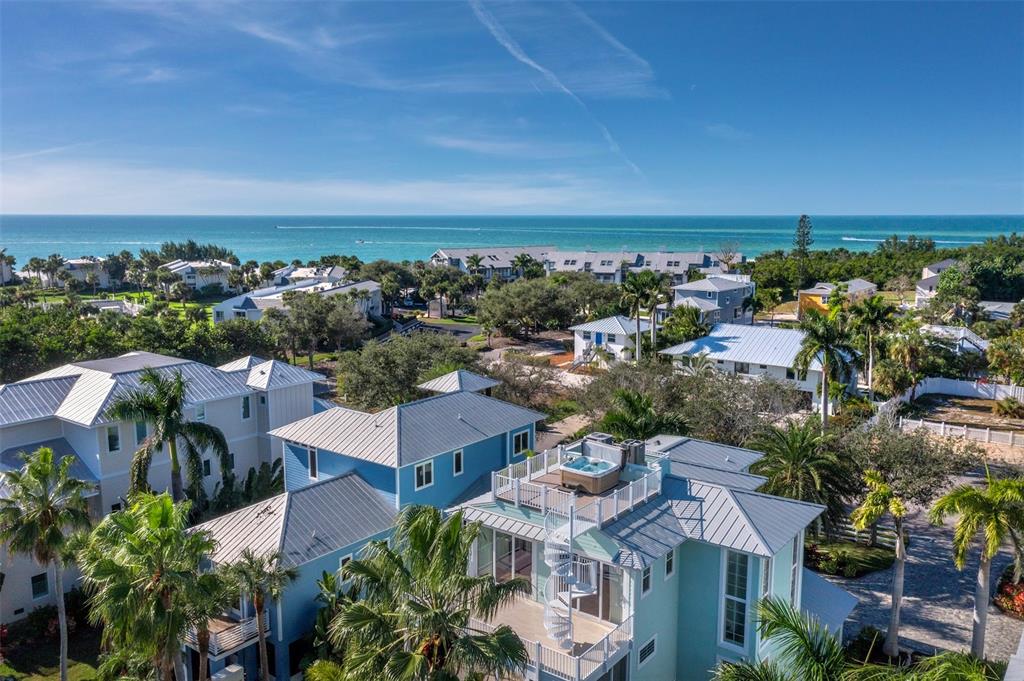 An aerial view shows coastal houses with metal roofs, palm trees, and a rooftop hot tub — 333 FIREHOUSE COURT, LONGBOAT KEY, FL