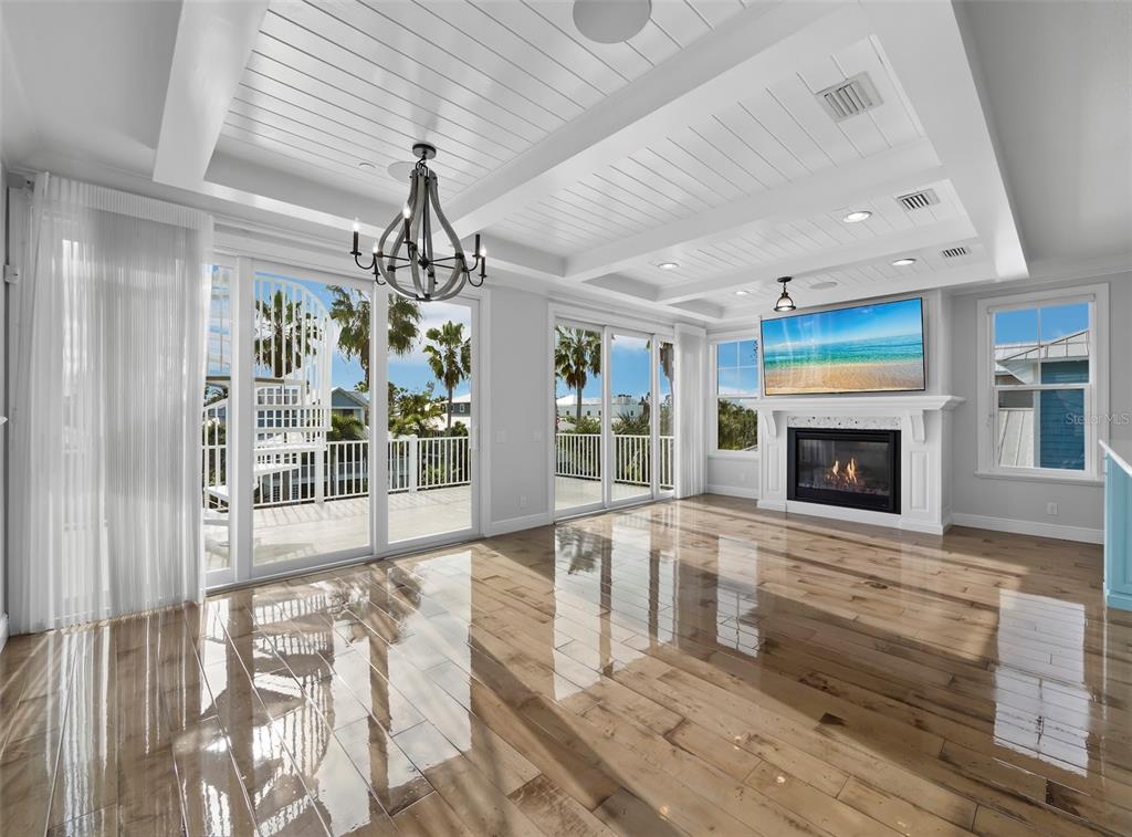A bright living room features a coffered ceiling, hardwood floors, a fireplace, and glass doors — 333 FIREHOUSE COURT, LONGBOAT KEY, FL