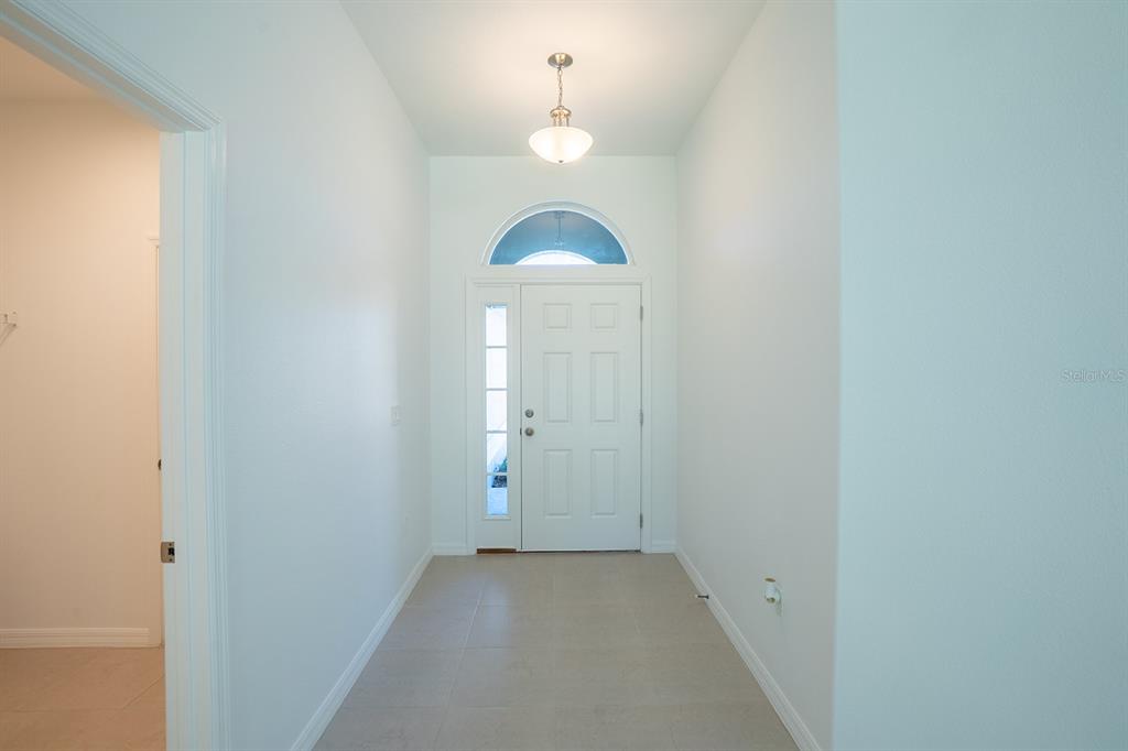 A bright entryway features a white front door with a sidelight and arched transom window — 91 FLEMINGWOOD LANE, PALM COAST, FL
