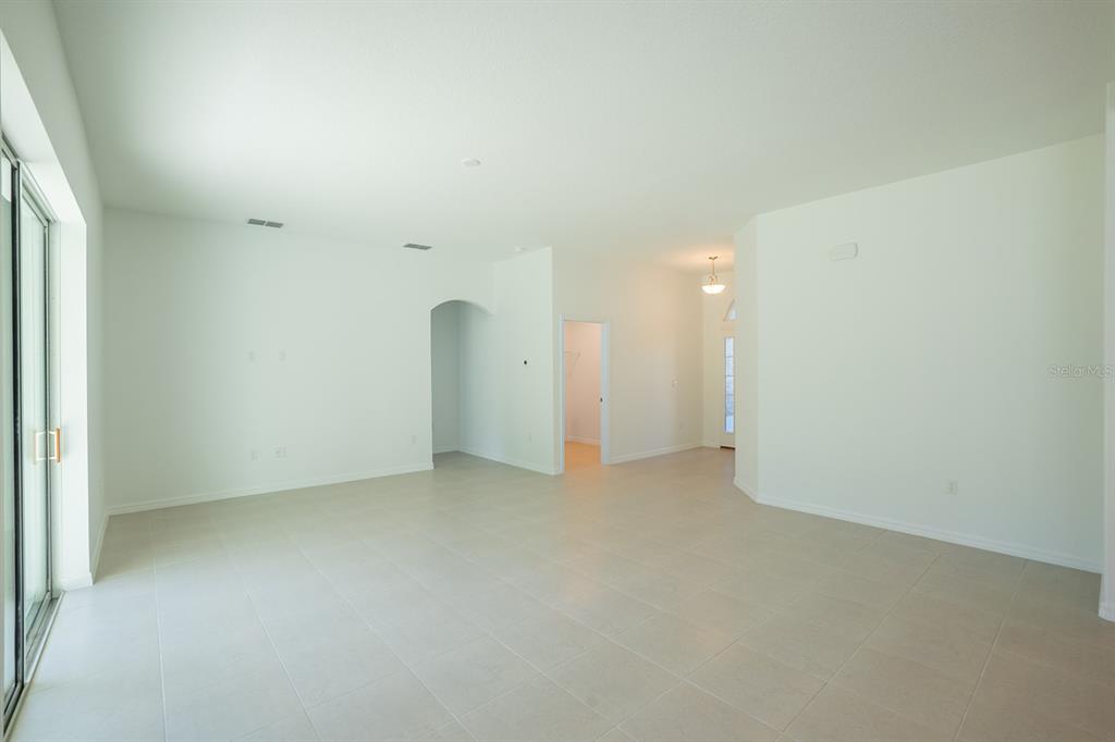An empty living room features white walls, light-colored tile flooring, and a sliding glass door — 91 FLEMINGWOOD LANE, PALM COAST, FL