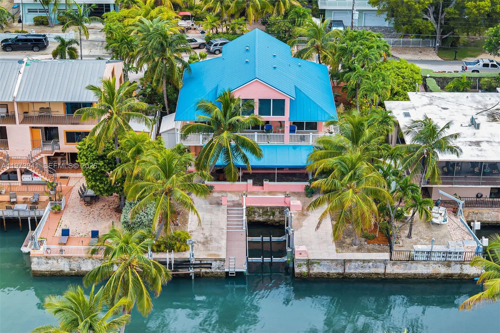 An aerial view shows a pink house with a blue metal roof and a boat slip — 1218 Mockingbird Rd, Key Largo FL 33037, KEY LARGO, FL